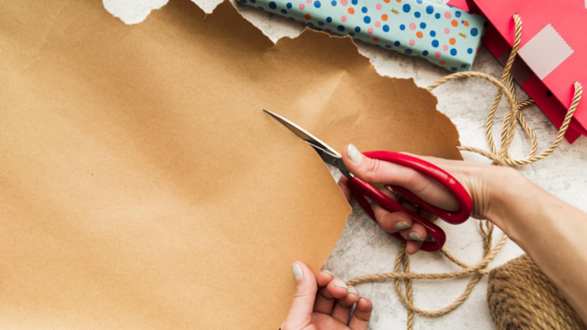overhead_view_person_s_hand_cutting_brown_paper_with_scissor_23_2148125337_07728400