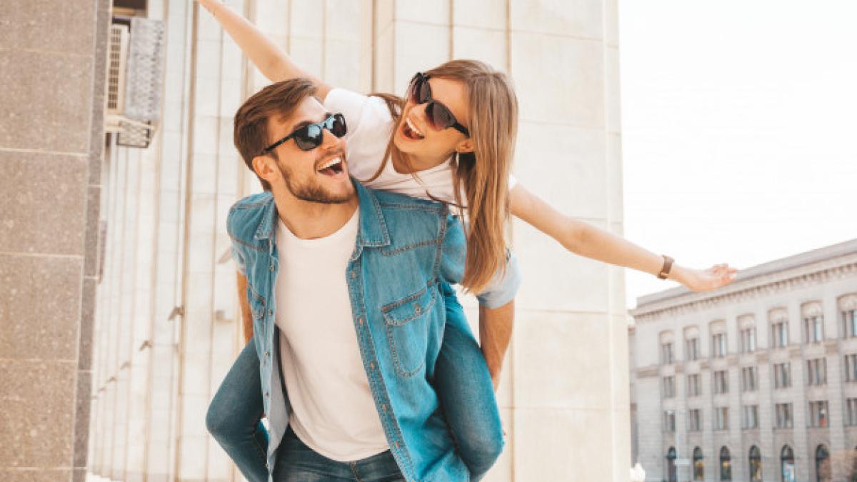 smiling_beautiful_girl_her_handsome_boyfriend_casual_summer_clothes_man_carrying_his_girlfriend_back_she_raising_her_hands_158538_5439_62515100