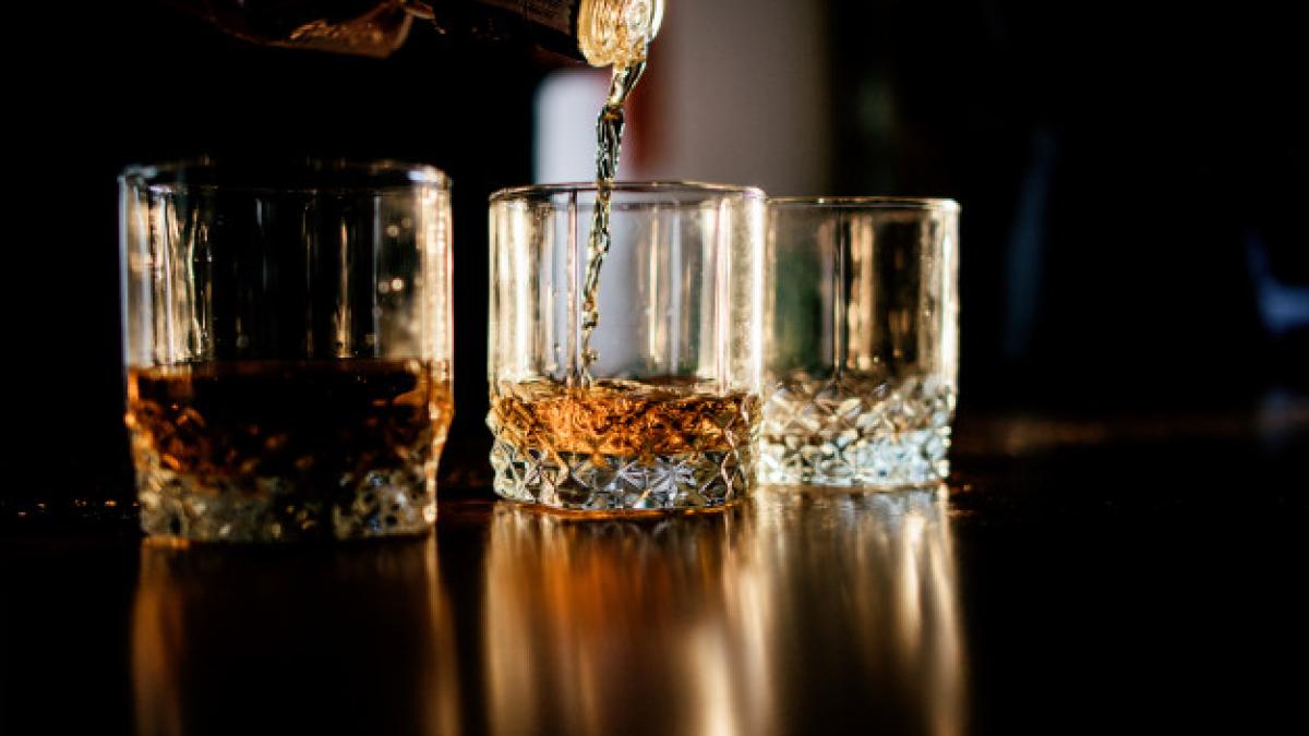 man_pours_whisky_glasses_standing_before_wooden_table_8353_4153_42166100