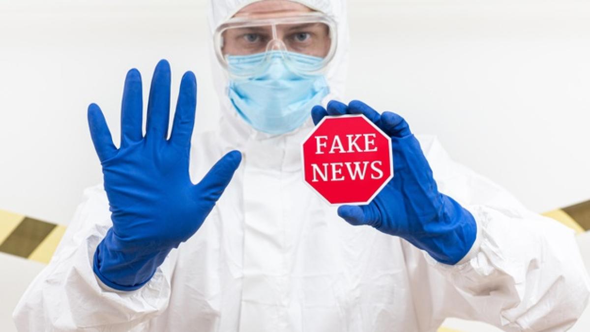 man_holding_badged_with_fake_news_23_2148552709_59985600