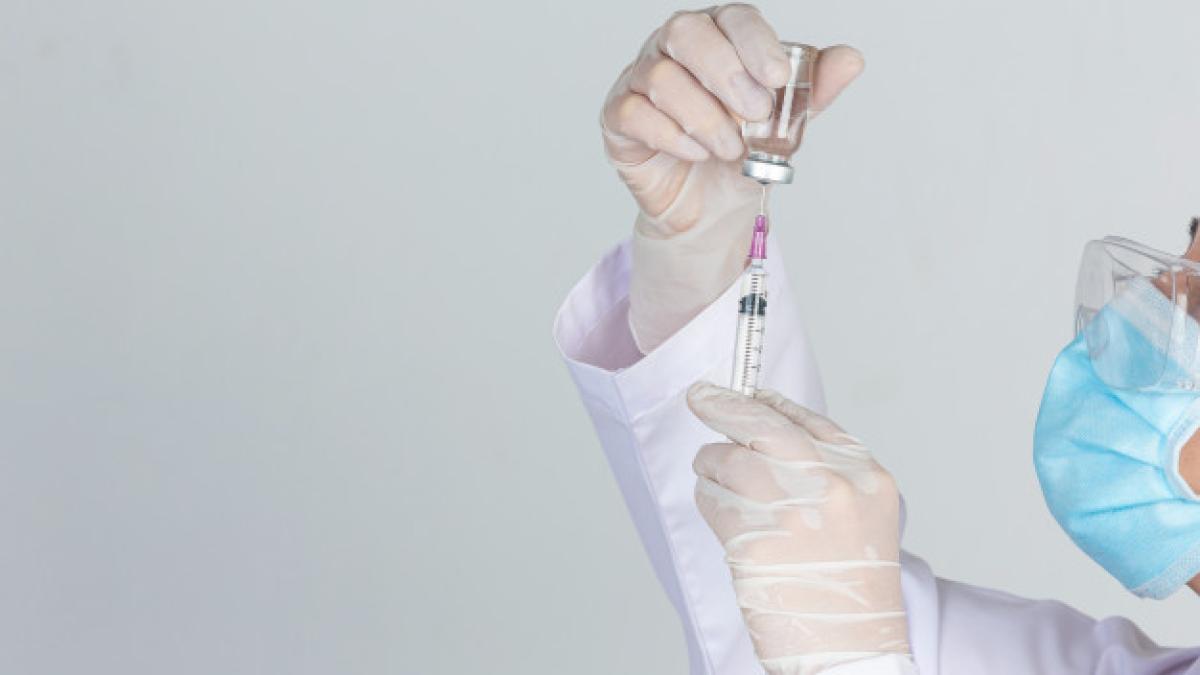 young_doctor_is_holding_hypodermic_syringe_with_vaccine_vial_rubber_gloves_gray_wall_1150_21810_27519900