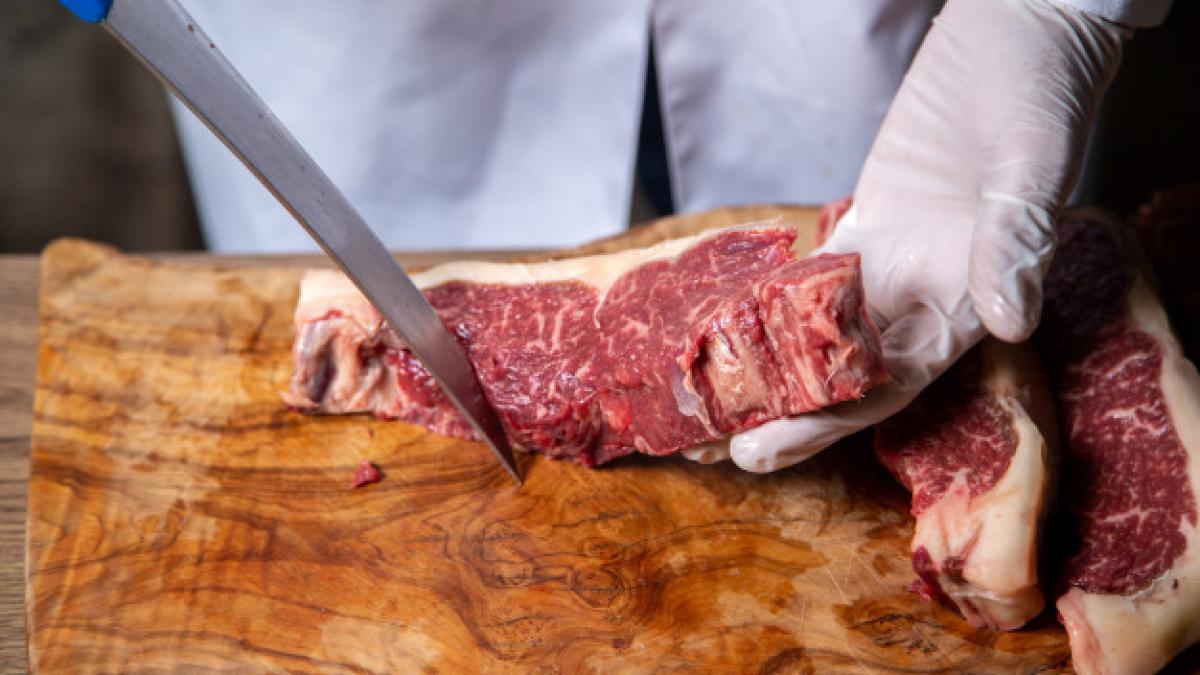 front_view_butcher_cutting_meat_white_gloves_holding_big_knife_wooden_desk_140725_20055_46464000