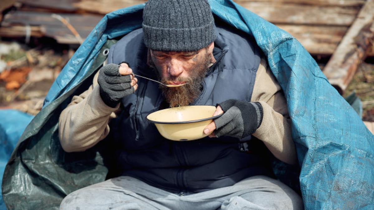 homeless_man_eats_soup_from_plate_near_ruins_helping_poor_hungry_people_during_epidemic_89718_688_37753800