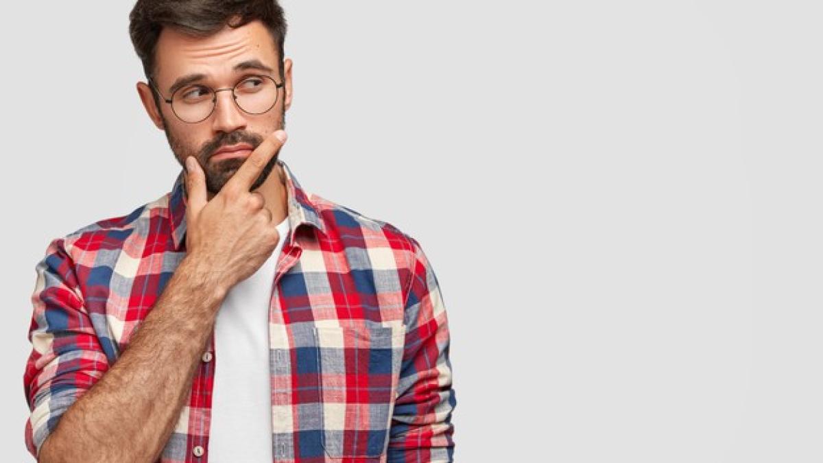 shot_pleasant_looking_bearded_male_holds_chin_looks_pensively_aside_holds_chin_focused_aside_stands_against_white_wall_273609_15069_42327600
