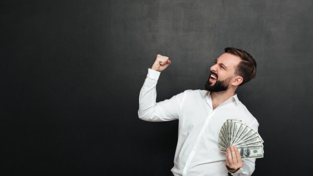 portrait-successful-guy-white-shirt-rejoicing-like-winner-with-fan-100-dollar-bills-hand-clenching-fist-aside-dark-gray_171337-590_31751600