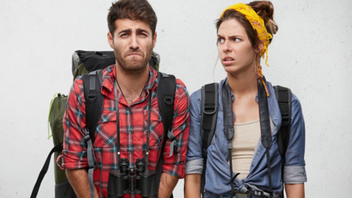 caucasian-male-taveler-looking-upset-while-wanting-go-toilet-holding-big-backpack-having-binoculars-his-neck-his-young-female-companion-who-is-looking-him-with-annoyance_273609-6_34392800
