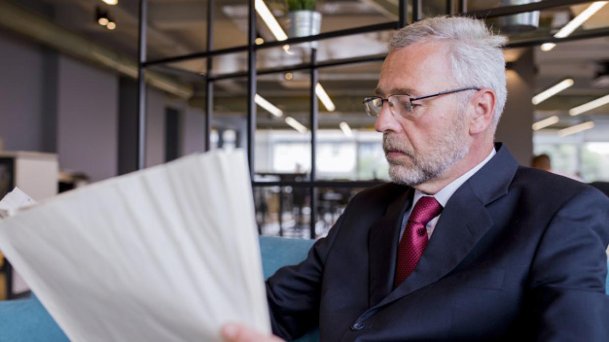 senior_businessman_sitting_reading_newspaper_office_23_2147923321_49886800
