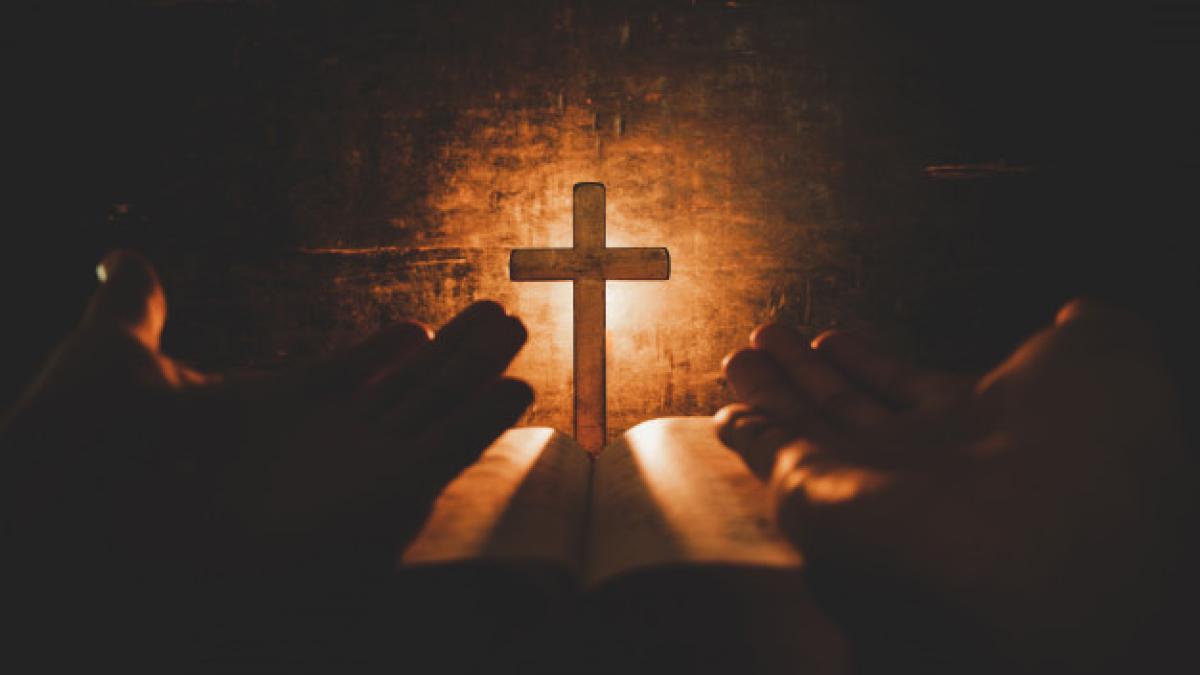 conceptual-image-focus-candle-light-with-man-hand-holding-wooden-cross-bible-blurred-world_1150-9230_36220300