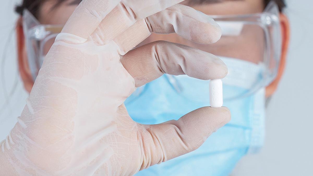 beautiful-young-doctor-is-wearing-mask-while-holding-medicine-with-rubber-gloves-gray-wall_79332400