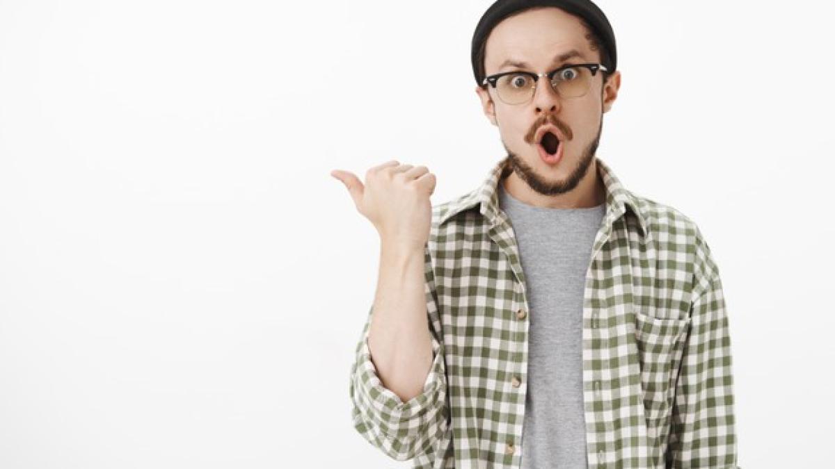 thrilled_impressed_young_hipster_guy_with_beard_checked_green_shirt_pointing_left_with_thumb_saying_wow_with_folded_lips_popping_eyes_from_amazement_gray_wall_176420_23553_59107800