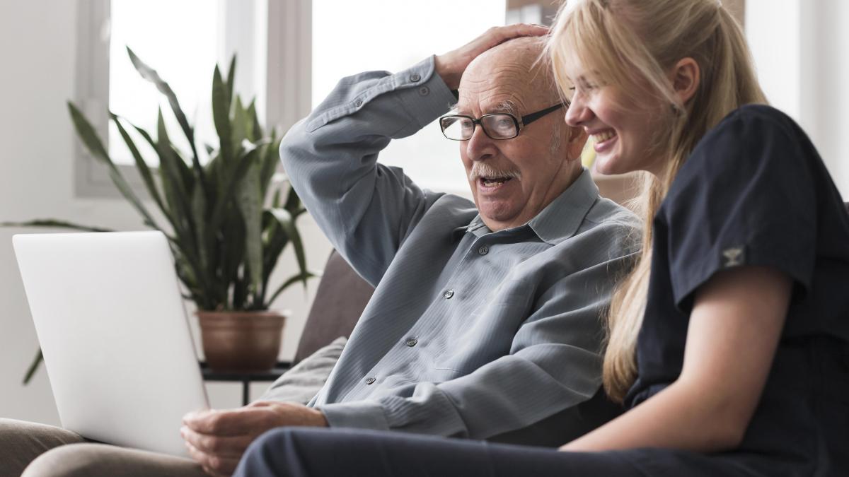 old-man-video-calling-family-from-nursing-home-with-nurse-s-help_49230600