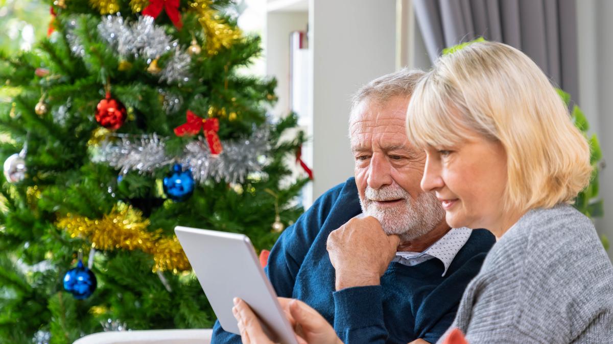 senior-couple-using-tablet-video-phone-call-greeting-their-family-christmas-festival-sitting-sofa-with-decoration-tree_99733200