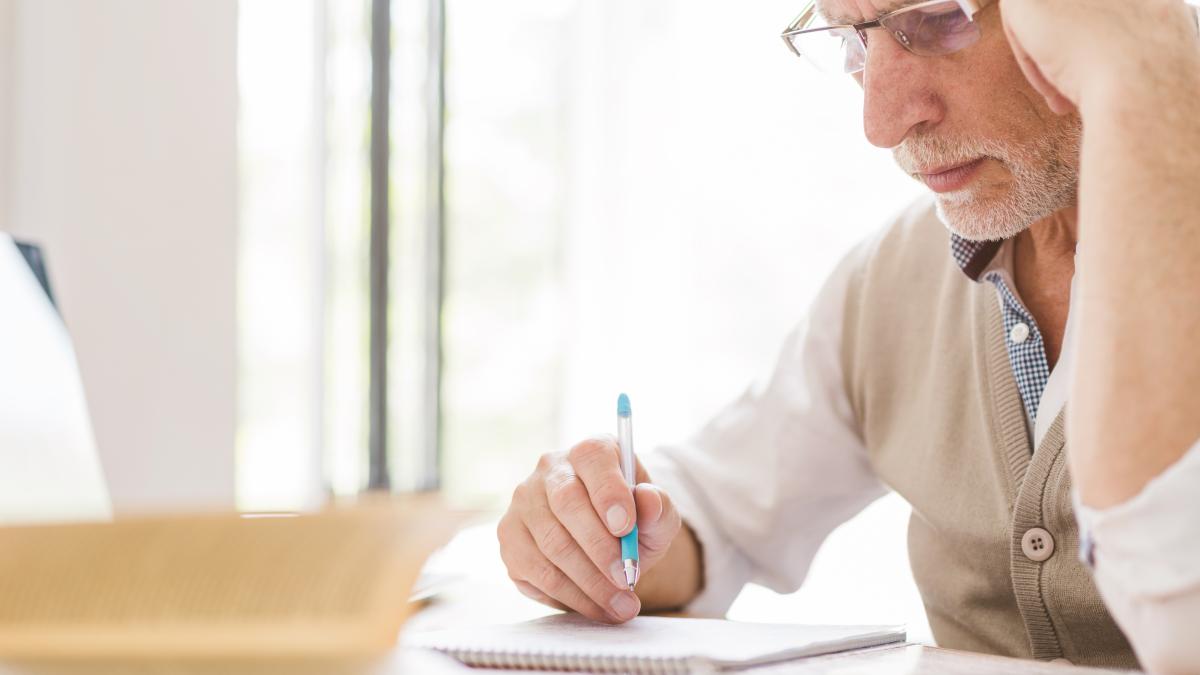 senior-professor-glasses-writing-notebook-classroom_77599000