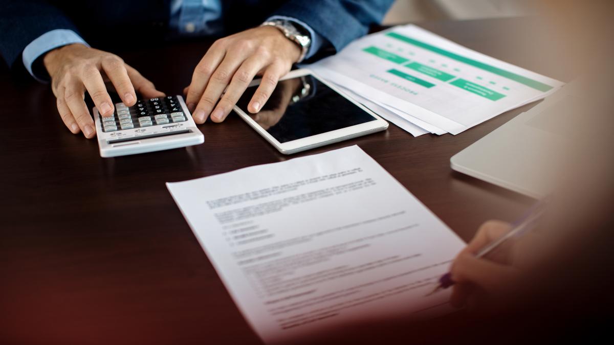 closeup-insurance-agent-making-calculations-while-signing-agreement-with-client-office_96000700