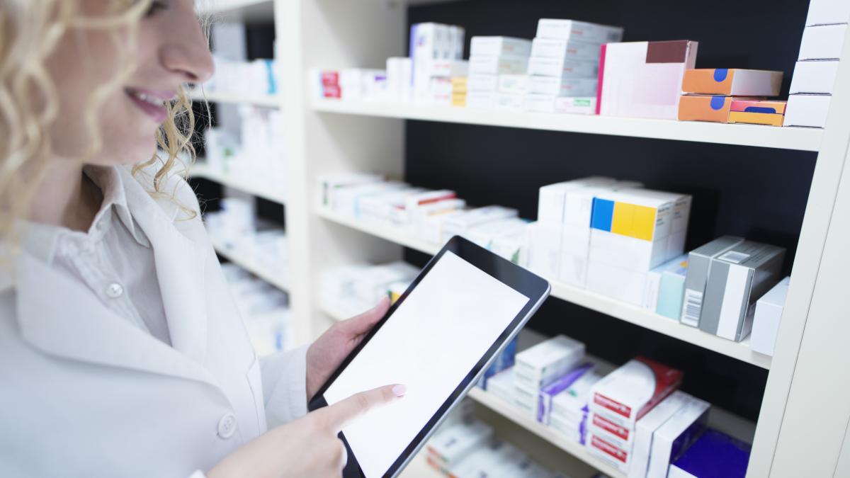 pharmacist-holding-tablet-by-shelf-full-medicine-drug-store-checking-medication-availability-specification_71452600