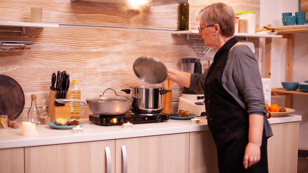 woman-preparing-food-gas-cooker-romantic-dinner-with-husband-retired-woman-cooking-nutritious-food-her-man-celebrate-relationship-anniversary_69992200