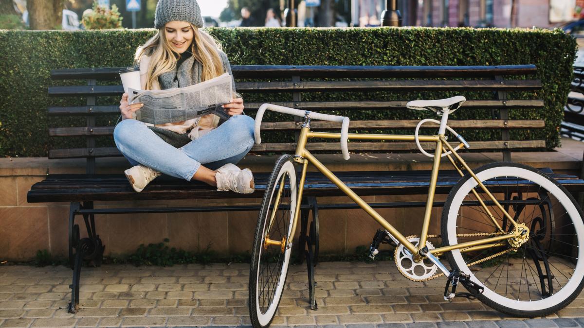pretty-woman-reading-newspaper-near-bicycle_14953000