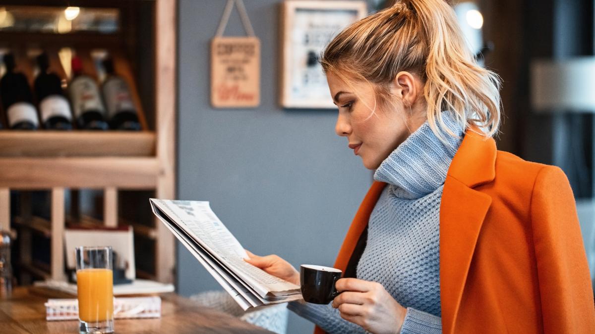 female-freelancer-relaxing-coffee-break-reading-newspaper-cafeteria_74941100