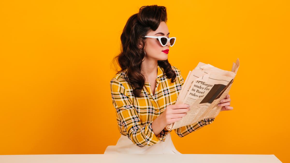 elegant-young-woman-reading-newspaper-studio-shot-concentrated-pinup-girl-posing-yellow-background_10466600