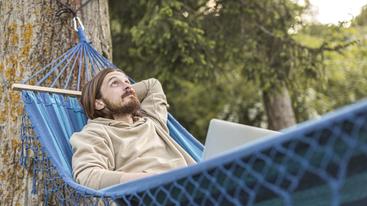 man-enjoying-his-time-nature-while-sitting-hammock_47923000