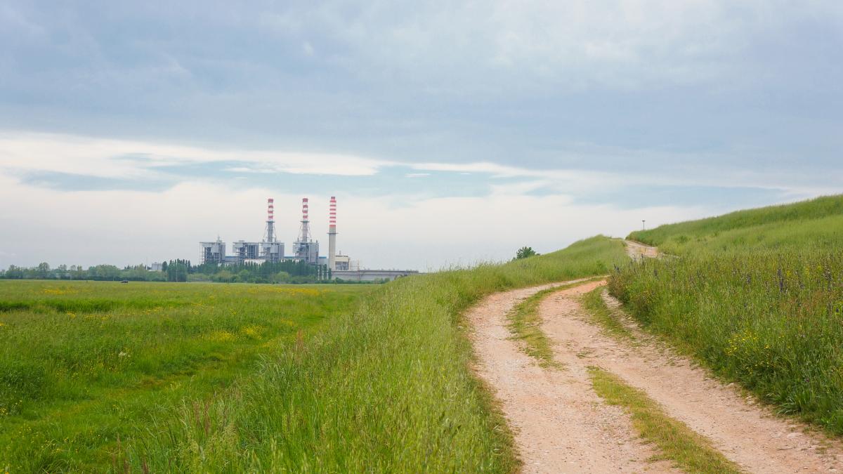 beautiful-shot-green-field-side-dirt-road-with-building-cloudy-sky_24727500