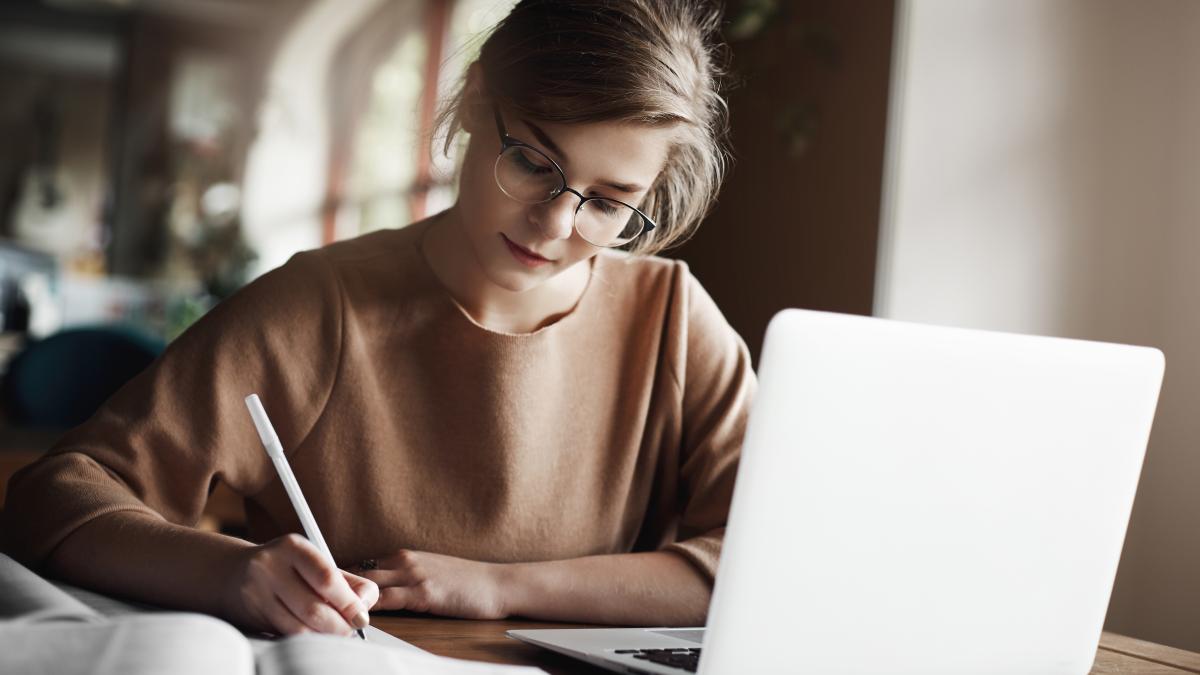 hardworking-focused-woman-trendy-glasses-concentrating-writing-essay-sitting-cozy-cafe-near-laptop-working-making-notes-carefully_57804300
