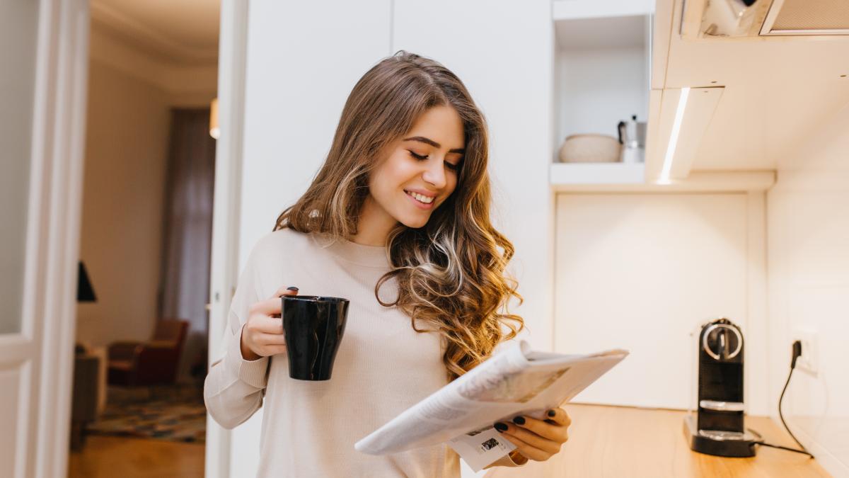 fascinating-female-model-with-light-brown-hair-reading-journal-her-kitchen_66125600