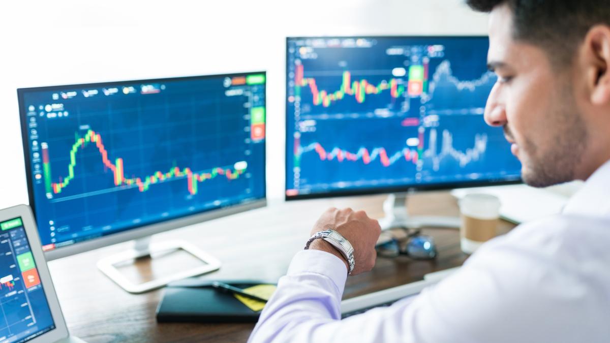 confident-male-stock-broker-waiting-stock-market-open-looking-his-watch-front-his-computer_58197800