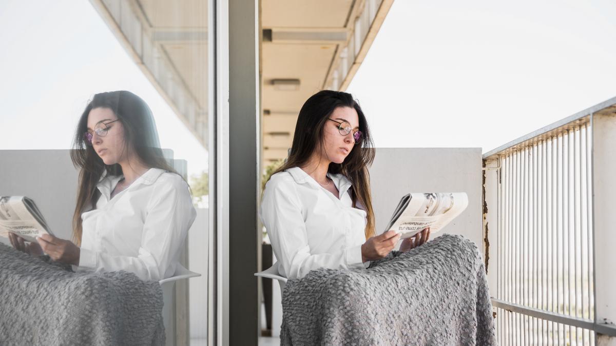 young-woman-reading-newspaper-balcony_73414900