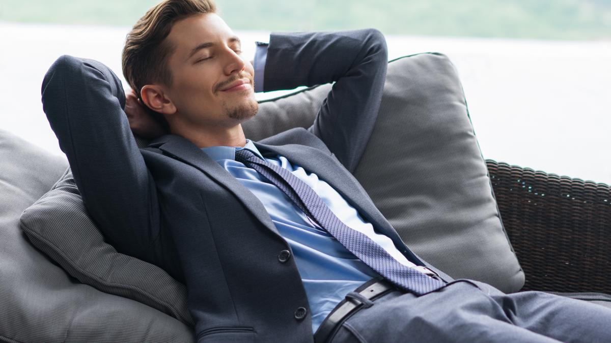 smiling-man-with-hands-head-dozing-couch_57329100