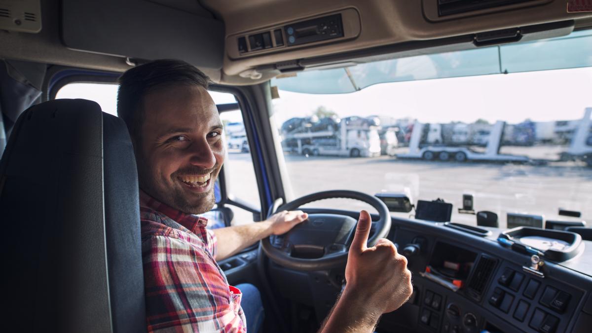 portrait-truck-driver-sitting-his-truck-holding-thumbs-up_30810900