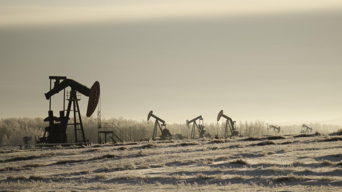 field-with-oil-pump-jacks-surrounded-by-greenery-cloudy-sky-sunlight_47045400