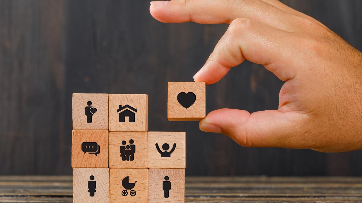 relationship-concept-wooden-table-side-view-hand-holding-wooden-cube-with-heart-icon_44547700