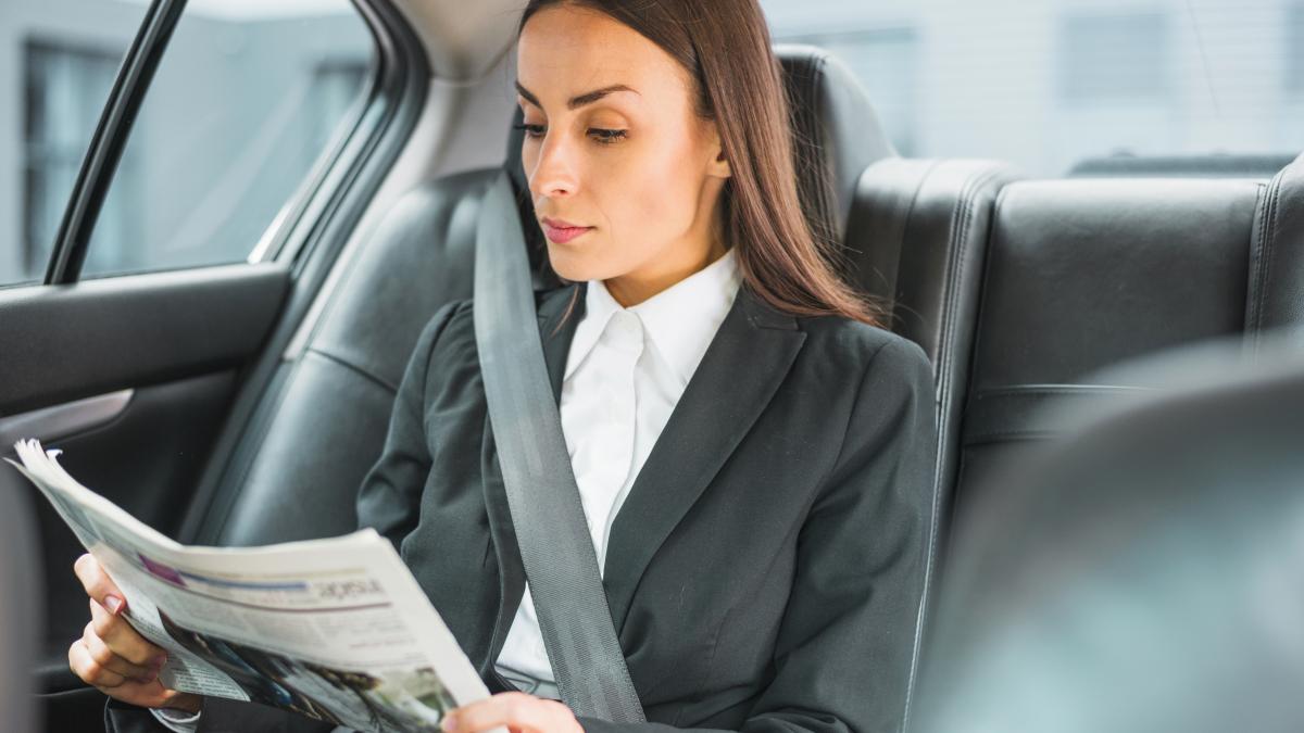 beautiful-young-businesswoman-traveling-by-car-reading-newspaper_00309900