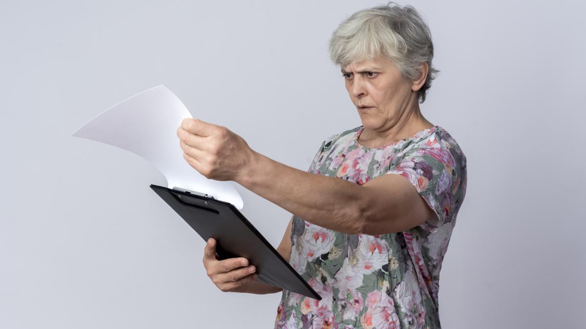 serious-elderly-woman-holds-looks-clipboard-isolated-white-wall_81130200