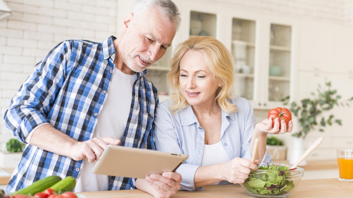 smiling-senior-couple-looking-digital-tablet-preparing-food-kitchen_45513200