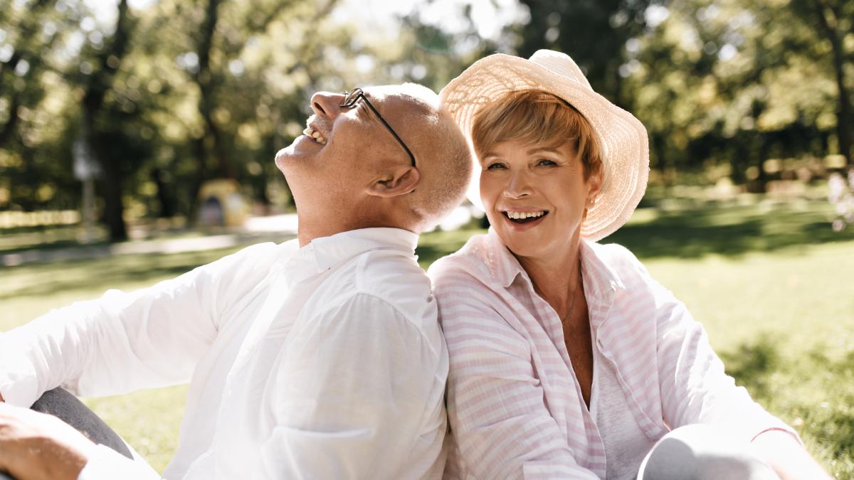 trendy-short-haired-lady-light-hat-striped-blouse-smiling-sitting-grass-with-old-man-glasses-white-shirt-outdoor_96182900