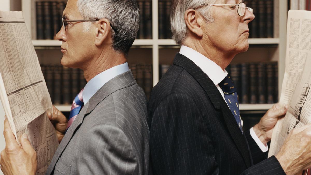 two-businessman-standing-back-to-back-and-reading-newspapers-1899895_29255300