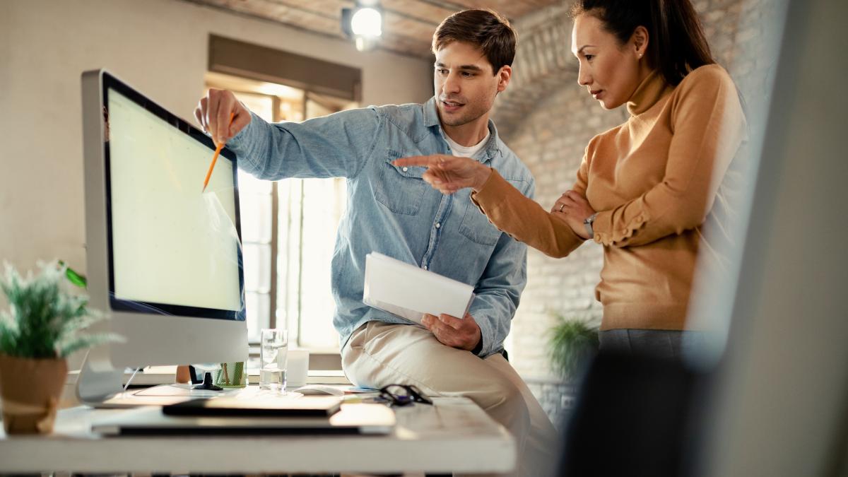 two-coworkers-cooperating-while-using-computer-working-office_36482200