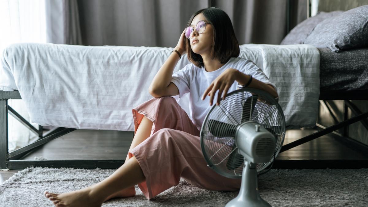 woman-wore-white-shirt-hand-placed-table-fan-looked-out_34657200