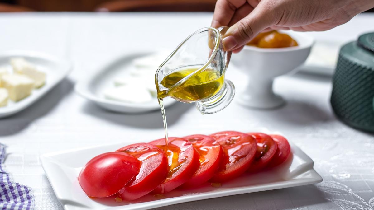 man-pours-olive-oil-sliced-tomatoes-side-view_24406100