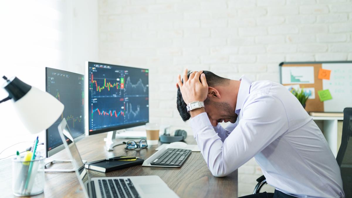 side-view-stressed-young-broker-sitting-with-head-hands-desk-while-working-from-home_89393300