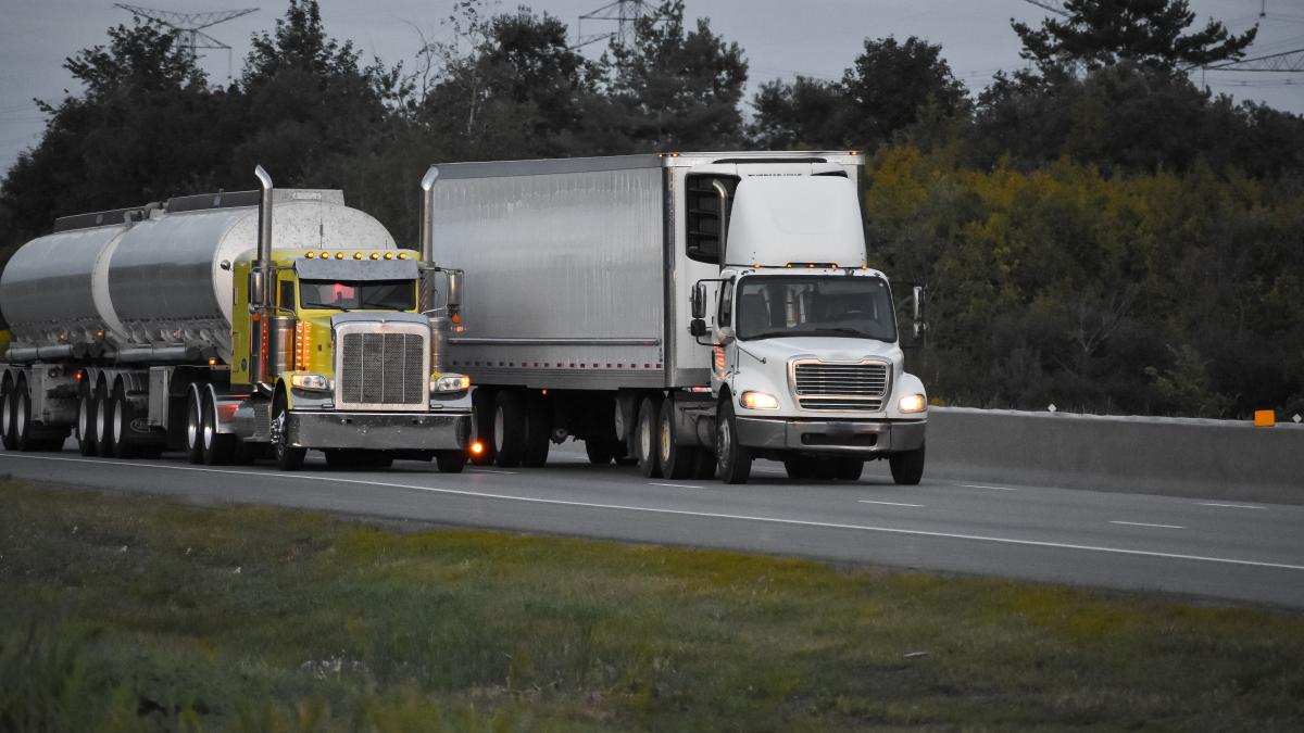 trailer-trucks-driving-road-surrounded-by-beautiful-green-trees_05976800