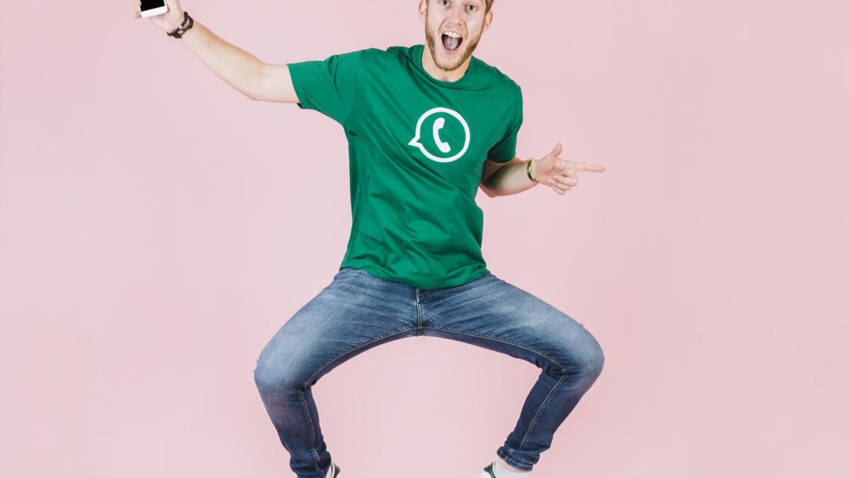 excited-man-with-smartphone-jumping-pink-backdrop_48502000