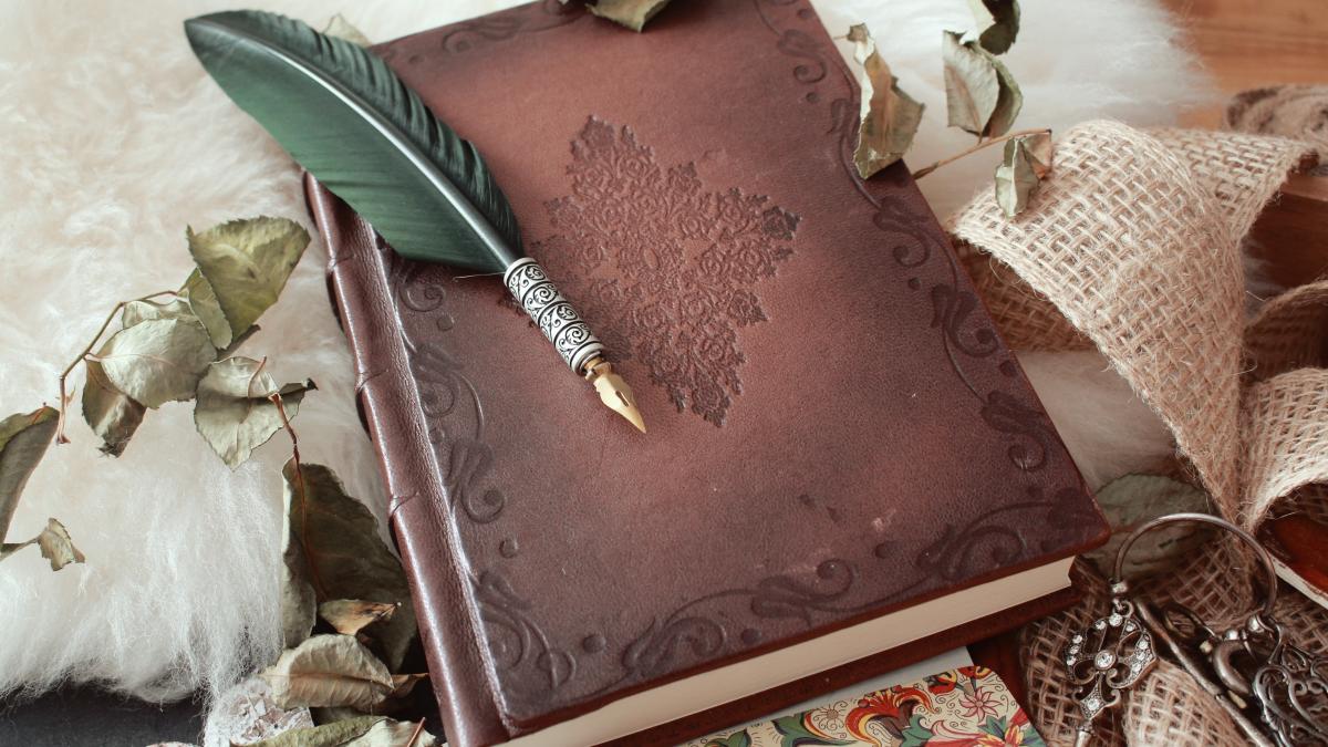 high-angle-shot-quill-pen-old-book-covered-with-dried-flower-petals_97103200