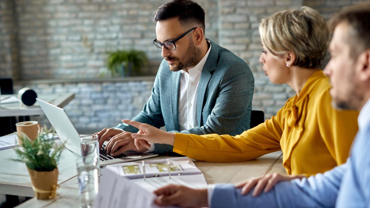 financial-advisor-working-computer-while-having-meeting-with-couple-office_95895700