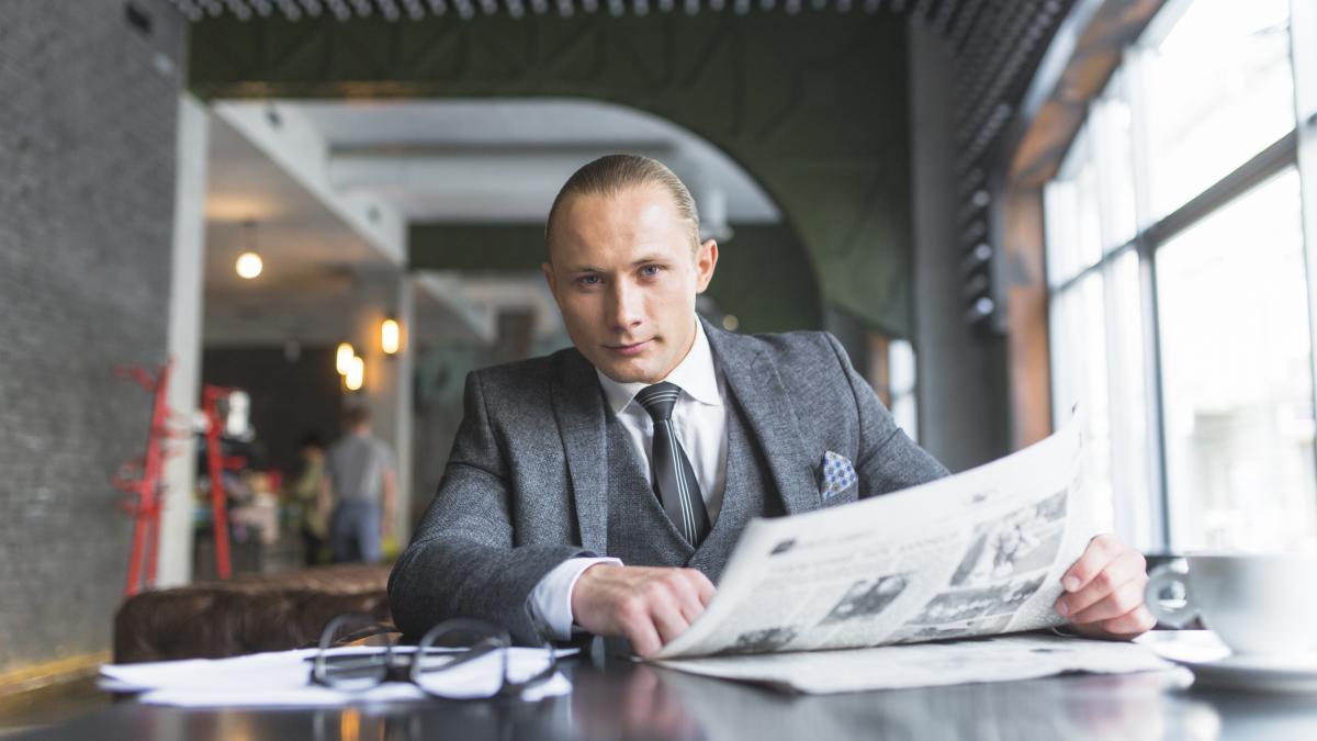 portrait-businessman-with-newspaper-sitting-caf_47923900