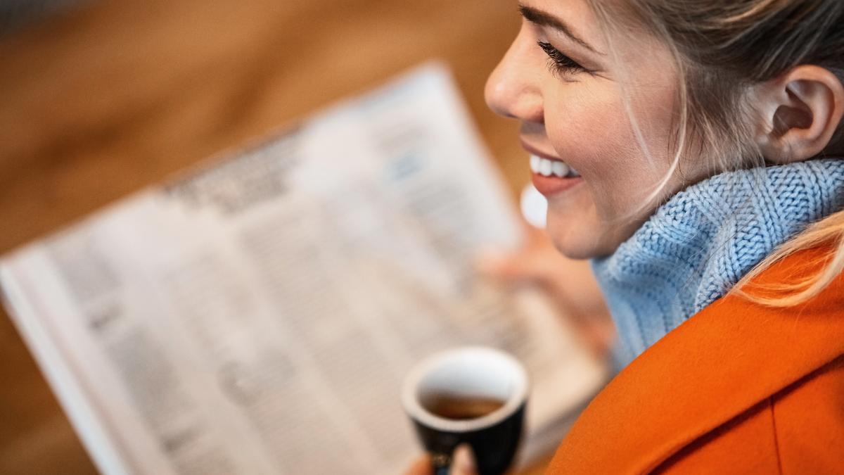 close-up-young-happy-businesswoman-having-coffee-while-reading-newspaper-cafe_24768300