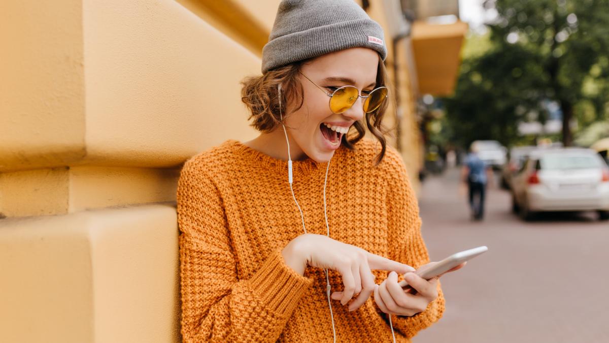 glad-girl-cozy-outfit-having-fun-outdoor-waiting-friend-walk-together-portrait-pretty-female-model-yellow-sweater-laughing-while-checking-mobile-mail-blur-street-background_07755000