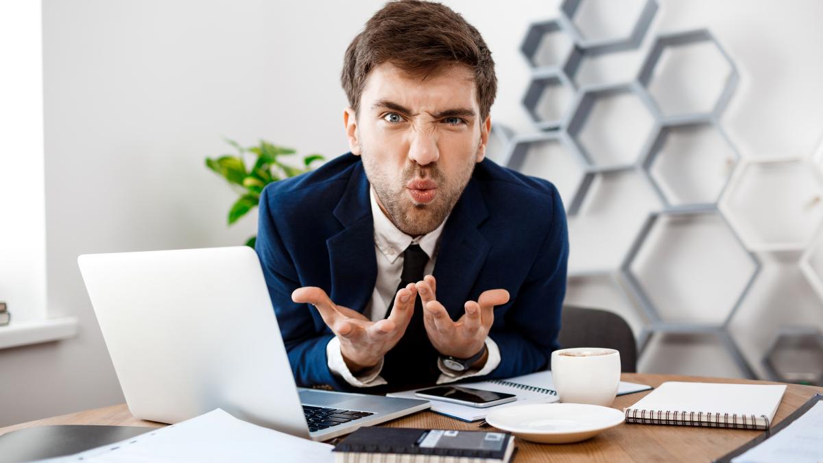 angry-young-businessman-sitting-workplace-office-background_77323700